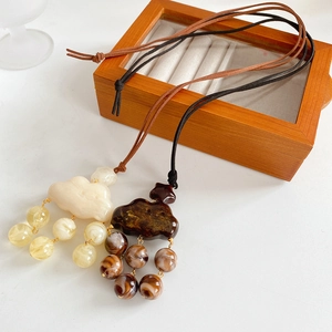 Detail of cloud-shaped resin pendants with dangling beads on suede cord necklaces