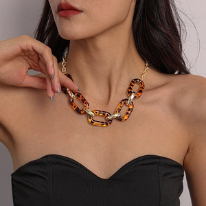 Detail of chunky leopard acrylic links and gold metal chain on a black background