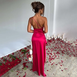 Détail d'une robe dos nu en satin rouge rose avec bougies romantiques et pétales au sol