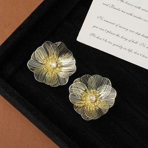 Close-up of golden hollow flower earrings with sparkling rhinestone on black display
