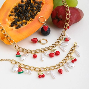 Detailed shot of gold fruit charms and pearls on necklace and bracelet set
