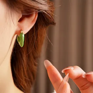 Vintage green enamel heart hoop earrings with gold-plated finish worn by model