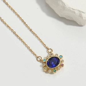 Macro shot of gold necklace featuring a blue oval stone surrounded by colorful gems