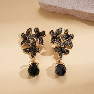 Detailed view of dark flower earrings with black rhinestones and hanging faceted beads