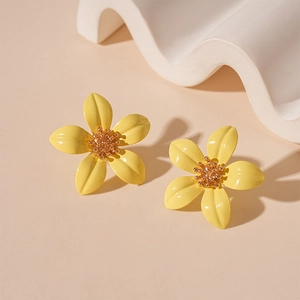 Detailed view of yellow five-petal flower earrings with golden seed bead centers