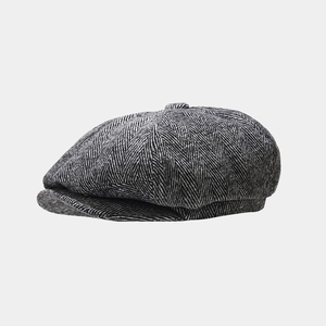 Detailed view of herringbone fabric and top button on a retro newsboy cap for men