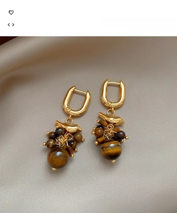 Detail of 18k gold bird earrings with tiger eye stone tassels on silk background