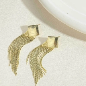 Detail of gold fringe earrings featuring a brushed square stud and elegant long chains