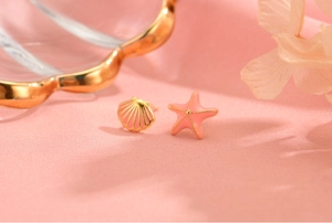 Detail of asymmetric pink enamel starfish and shell stud earrings in gold finish
