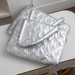 Detailed view of silver quilted laptop bag featuring elegant bow-tie patterns and zipper
