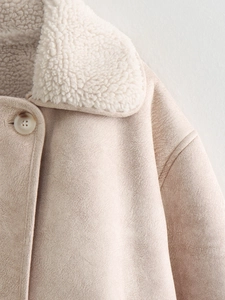 Detailed close-up of suede coat collar with soft faux fur lining and button detail