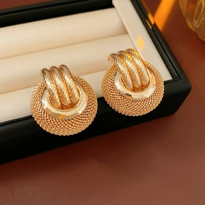 Macro shot of gold mesh ball earrings with a woven metallic texture and polished loop