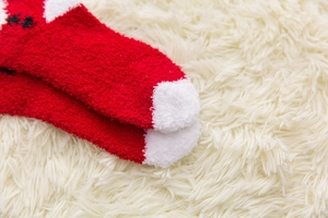 Close-up of soft red and white Christmas socks in plush coral fleece on white rug