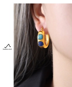 Detail view of gold stainless steel hoop earrings inlaid with turquoise and blue stones