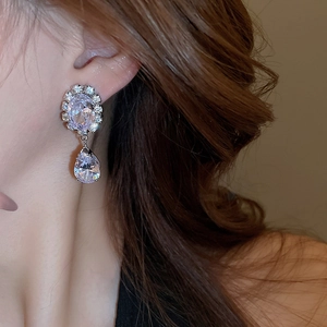 Detail of elegant teardrop purple crystal earrings worn by model for a luxury look