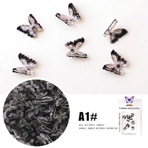 Macro detail of 3D resin butterfly nail charms with black and white ink gradient