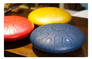 Close-up of colorful steel tongue drums in red, yellow, and textured navy blue