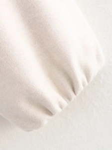 Gros plan détaillé des poignets en tissu doux blanc crème avec des coutures plissées