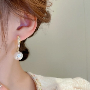 Close-up of elegant gold pearl drop earring with cubic zirconia on a female model