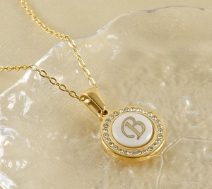 Détail du collier doré avec lettre B, incrustation de nacre et halo de cristaux brillants