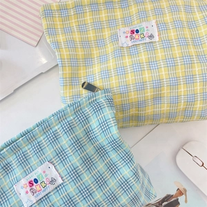 Dettaglio di borse per trucco in tela con etichette colorate e motivi a quadri plaid
