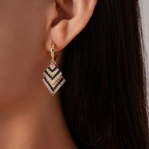 Close-up of geometric double-diamond gold earrings with black and white zircon inlay