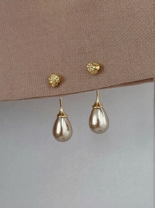 Close-up of golden irregular stud earrings with elegant drop-shaped champagne pearls