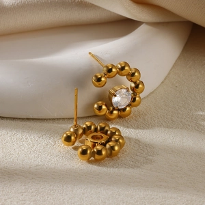 Detailed macro view of gold-plated flower stud earrings with zircon and pearl accents