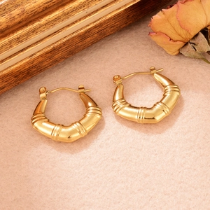 Vue détaillée de boucles d'oreilles dorées torsadées en U avec finition texturée