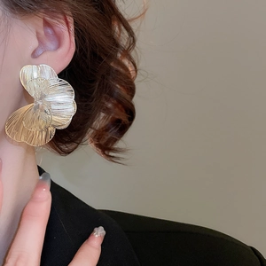 Gros plan de boucles d'oreilles fleurs dorées avec textures de pétales superposés