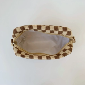 Detailed view of brown checkered knit makeup bag with zipper closure and white lining