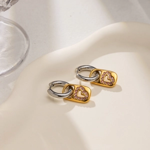 Détail de boucles d'oreilles bicolores en or 18 carats avec pendentif cœur en strass