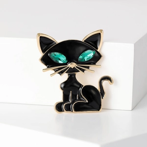 Macro detail of cat brooch featuring black enamel and sparkling green crystal eyes