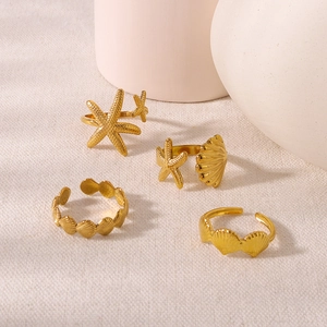 Golden ocean series rings set with starfish and seashell designs on white fabric background