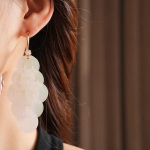 Macro view of long C-shaped tassel earrings with iridescent sequins and sparkling zircon
