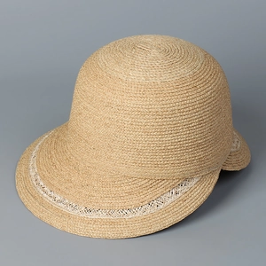 Detailed view of beige raffia straw hat featuring elegant white hollow woven trim