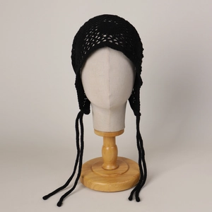 Détail du bonnet au crochet noir avec fleurs ajourées et longues lanières à nouer