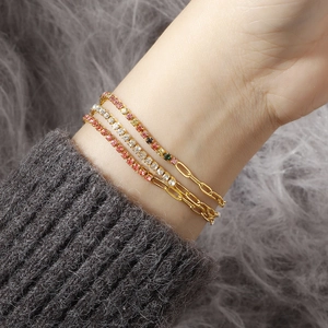 Close-up of three gold titanium bracelets with colorful zircon stones on a plush background