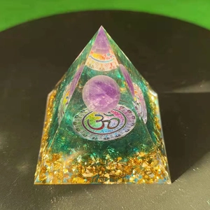 Macro shot of an Orgone pyramid with gold foil, purple crystal ball and Om symbol