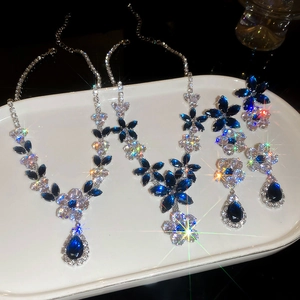 Detailed close-up of a silver flower jewelry set with blue zircons on a white tray