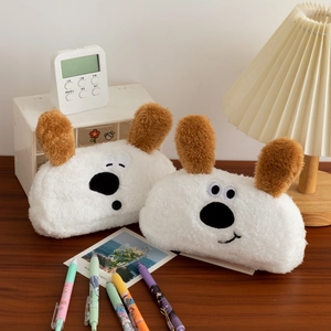 Close-up of cute plush dog pencil cases with embroidered faces on a wooden desk