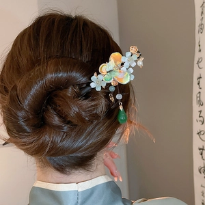 Detail of butterfly and flower hair stick with green pendant on elegant bun