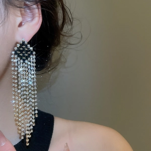 Macro detail of long silver fringe earrings with sparkling rhinestones on a model