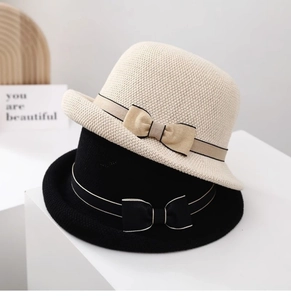 Dettaglio della trama a maglia e nastro con fiocco su cappelli da sole beige e neri