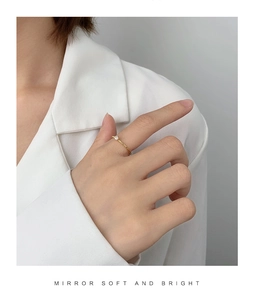 Minimalist gold plated ring with a single zircon stone worn by a model in white