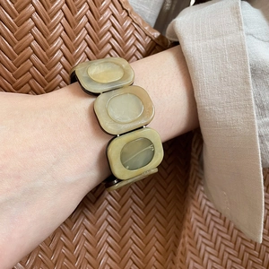 Detailed shot of beige marble resin square stretch bracelet on wrist with linen sleeve