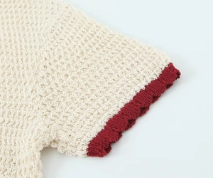 Detail of off-white knit polo shirt with contrast burgundy ribbed cuffs and textures