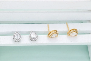 Detailed view of gold and silver teardrop stud earrings with pavé cubic zirconia