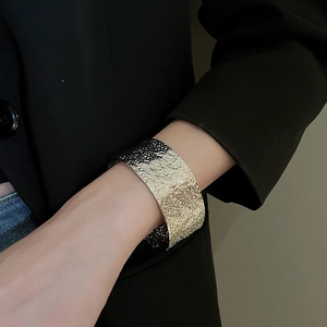 Close-up of wide silver open cuff bracelet with hammered texture on a model wearing black