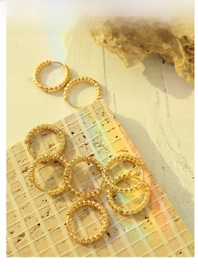 Detailed view of 18K gold plated textured hoop earrings set on natural stone background